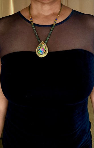 Model wearing evening dress adorned with colorful teardrop shaped dichroic glass set in a handcrafted brass pendant and a beaded leather necklace. By 3D Glass Designs.  