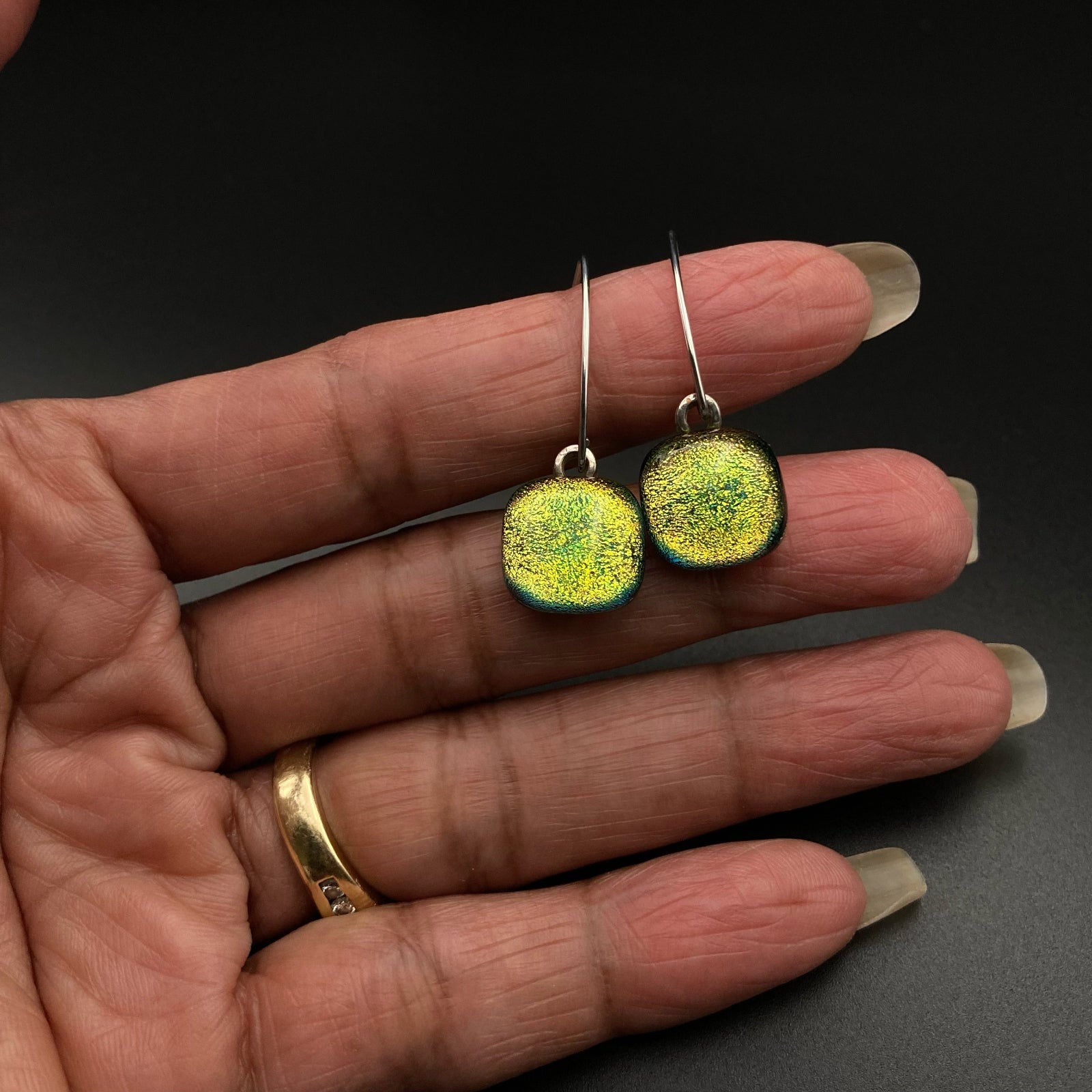Hand holding yellow fused glass earrings, by 3D Glass Designs.