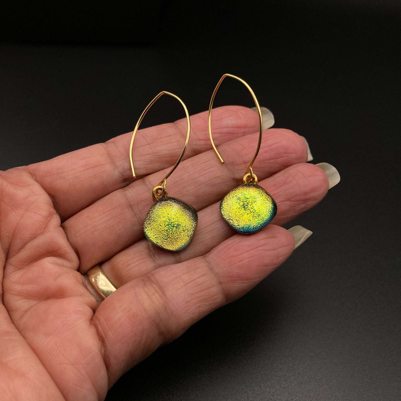Hand holding yellow glass dangle earrings with gold ear wires, by 3D Glass Designs.