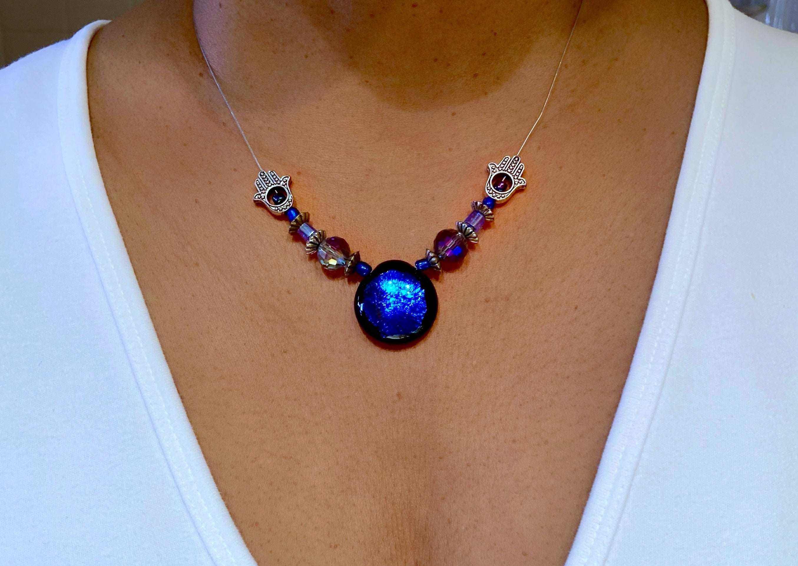 Model wearing beaded blue necklace with crystals and hamsa hand beads, by 3D Glass Designs.