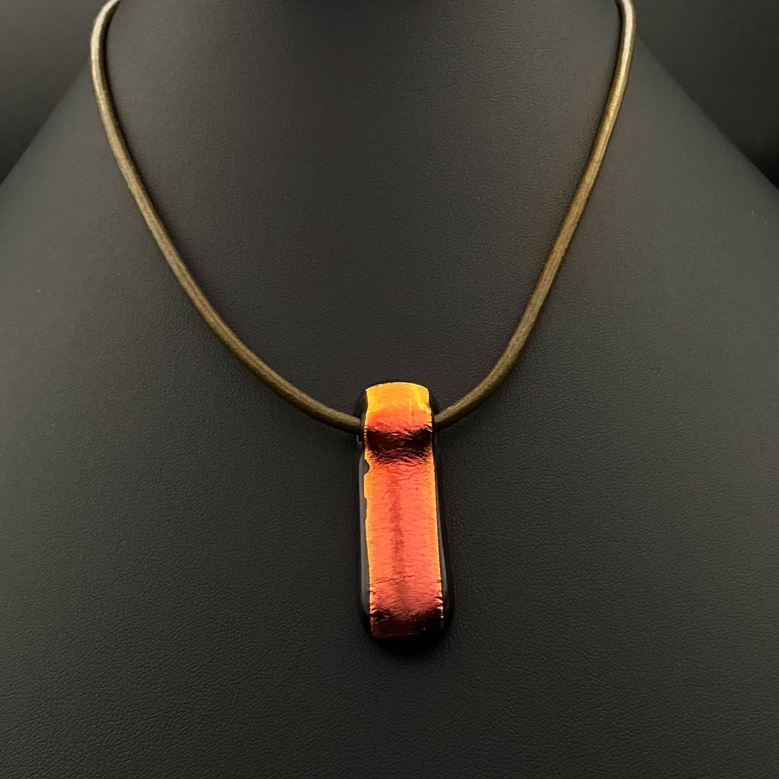 Long red fused glass pendant on an olive-green leather cord, by 3D Glass Designs.