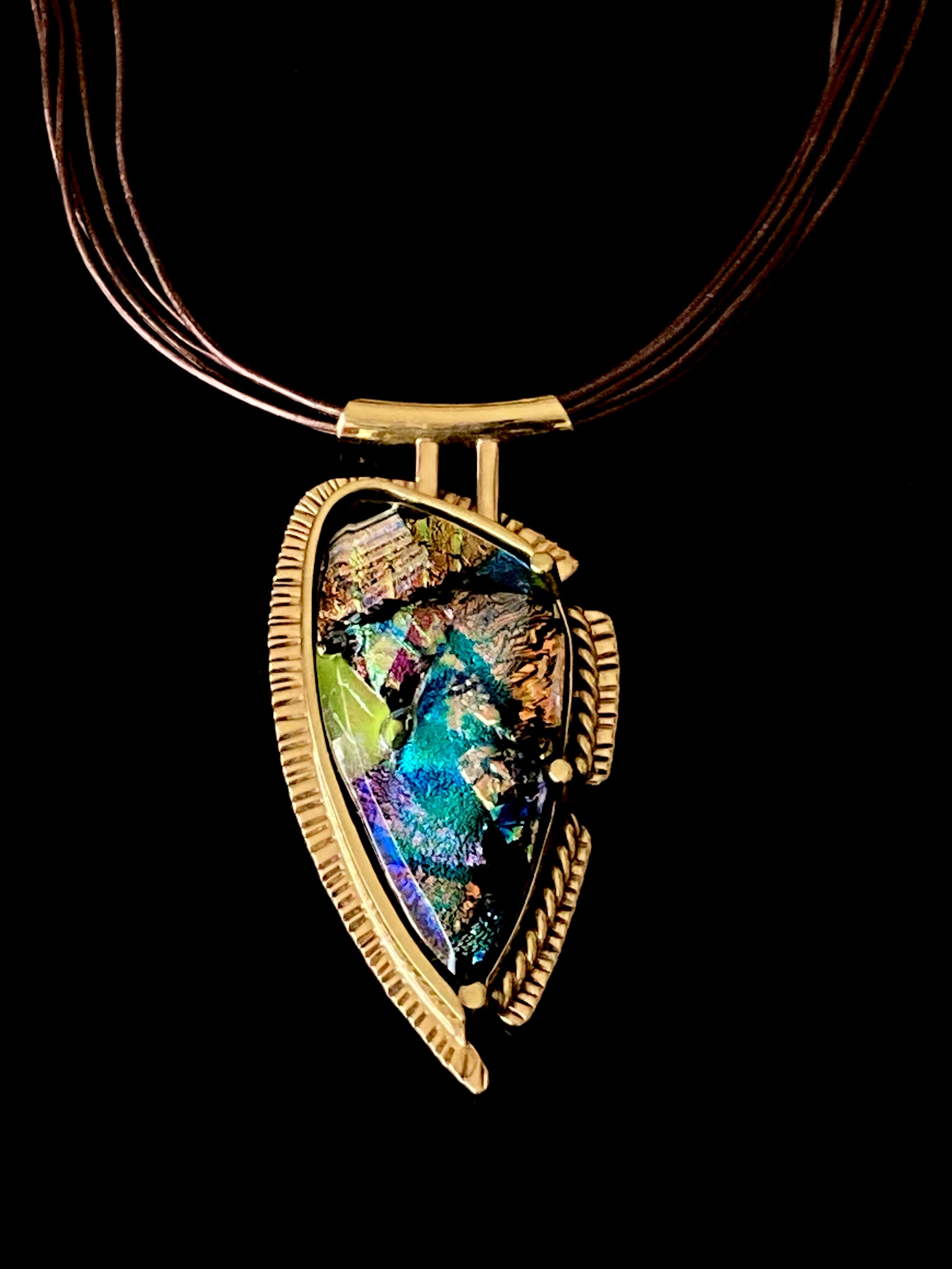 Handcrafted brass pendant featuring multicolored dichroic glass in a shield-shape hung on a multistrand leather necklace, by 3D Glass Designs.