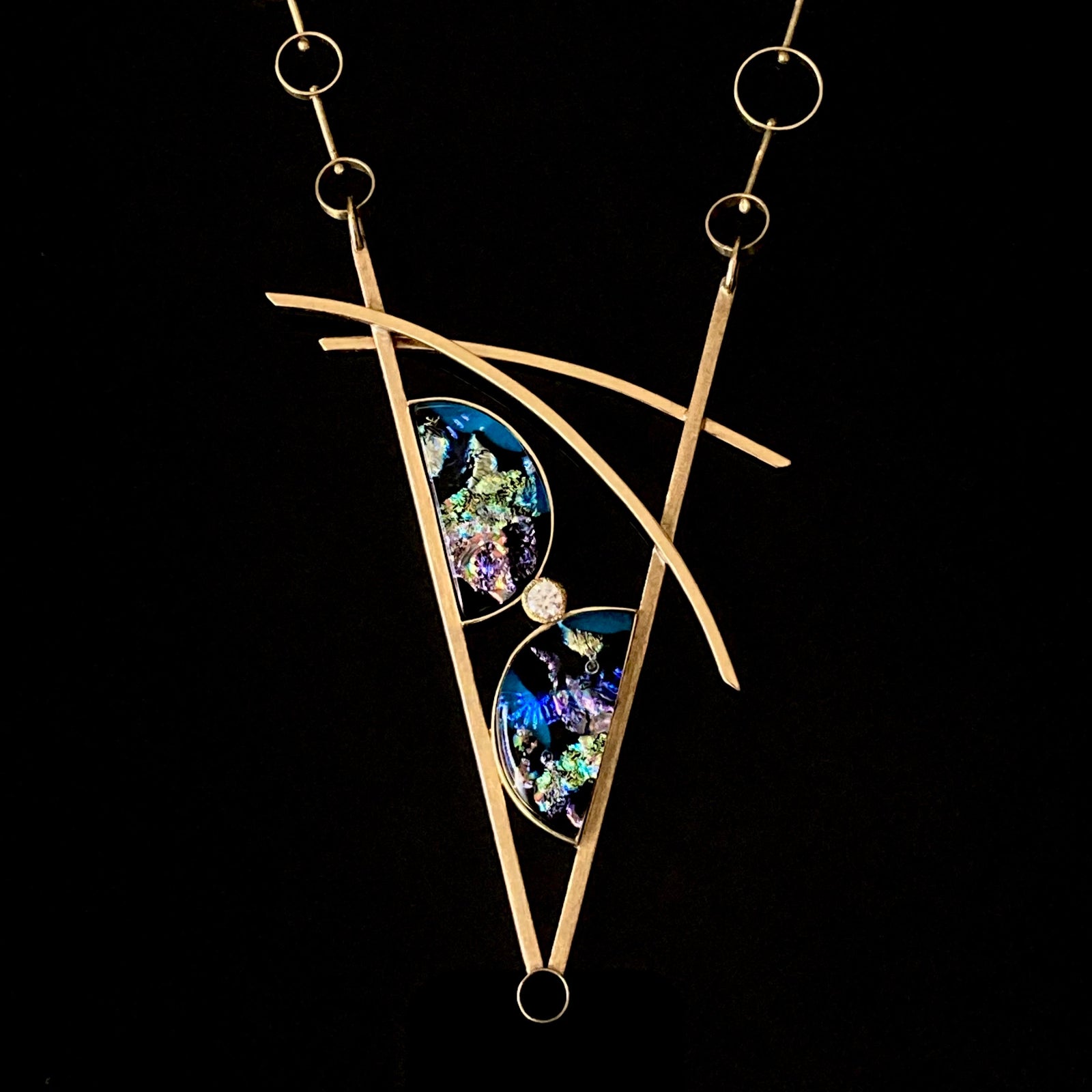 Geometric inspired brass pendant with teal fused glass in semi-circles and CZ, framed in a V with two slightly curved arch's above.  Necklace made of various sized circles linked together, by 3D Glass Designs.