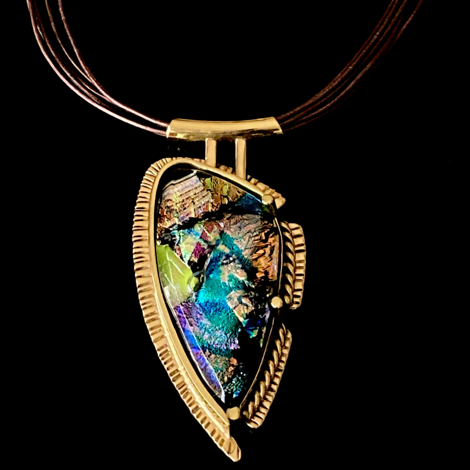 Handcrafted brass pendant featuring multicolored dichroic glass in a shield-shape hung on a multistrand leather necklace, by 3D Glass Designs.