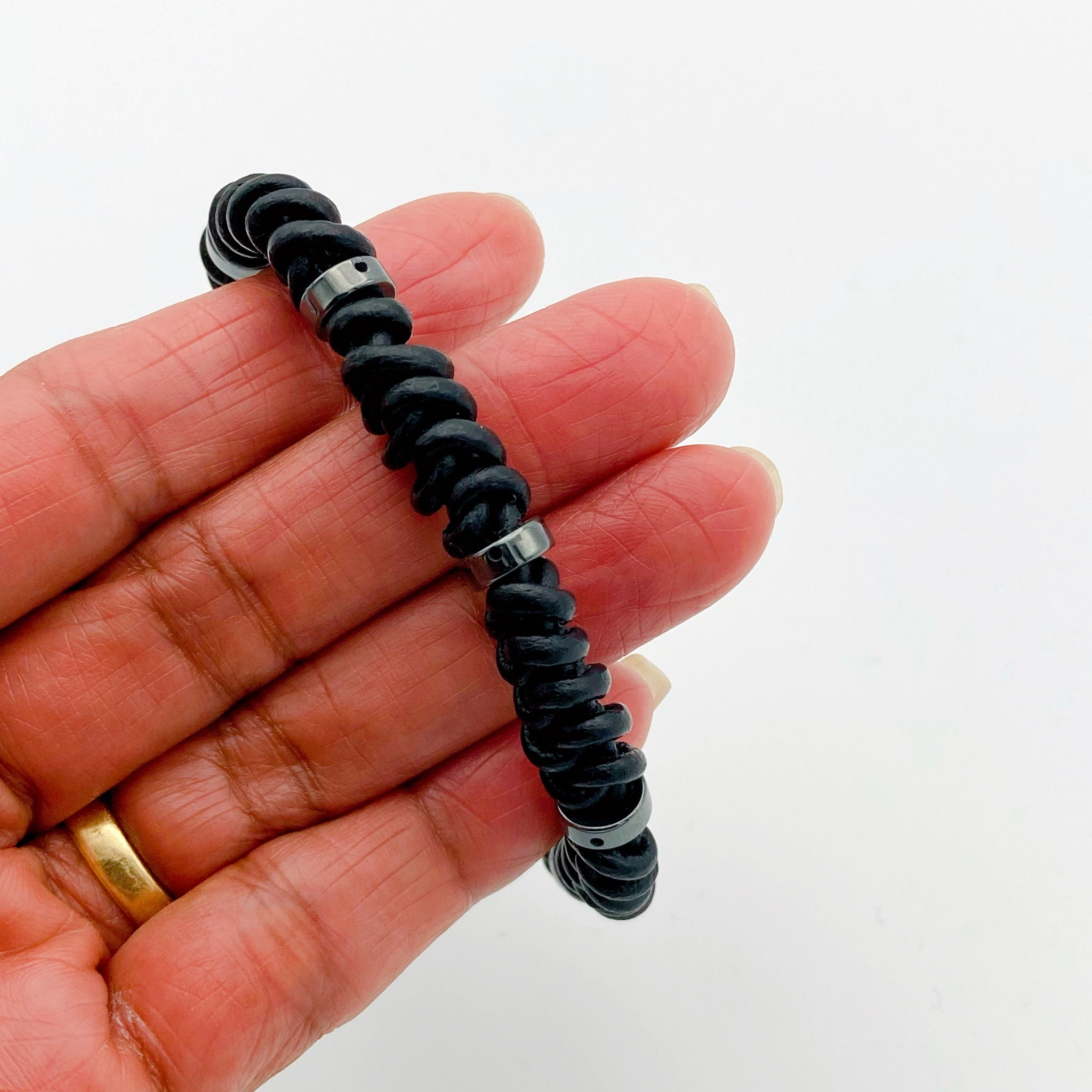 Hand holding black macrame leather bracelet, by 3D lass Designs.