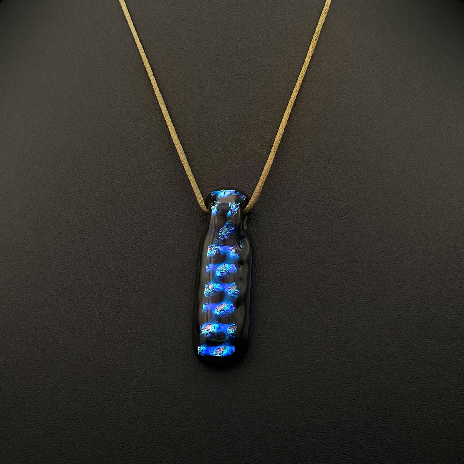 Long fused glass pendant on a stain cord against a black background, by 3D Glass Designs.