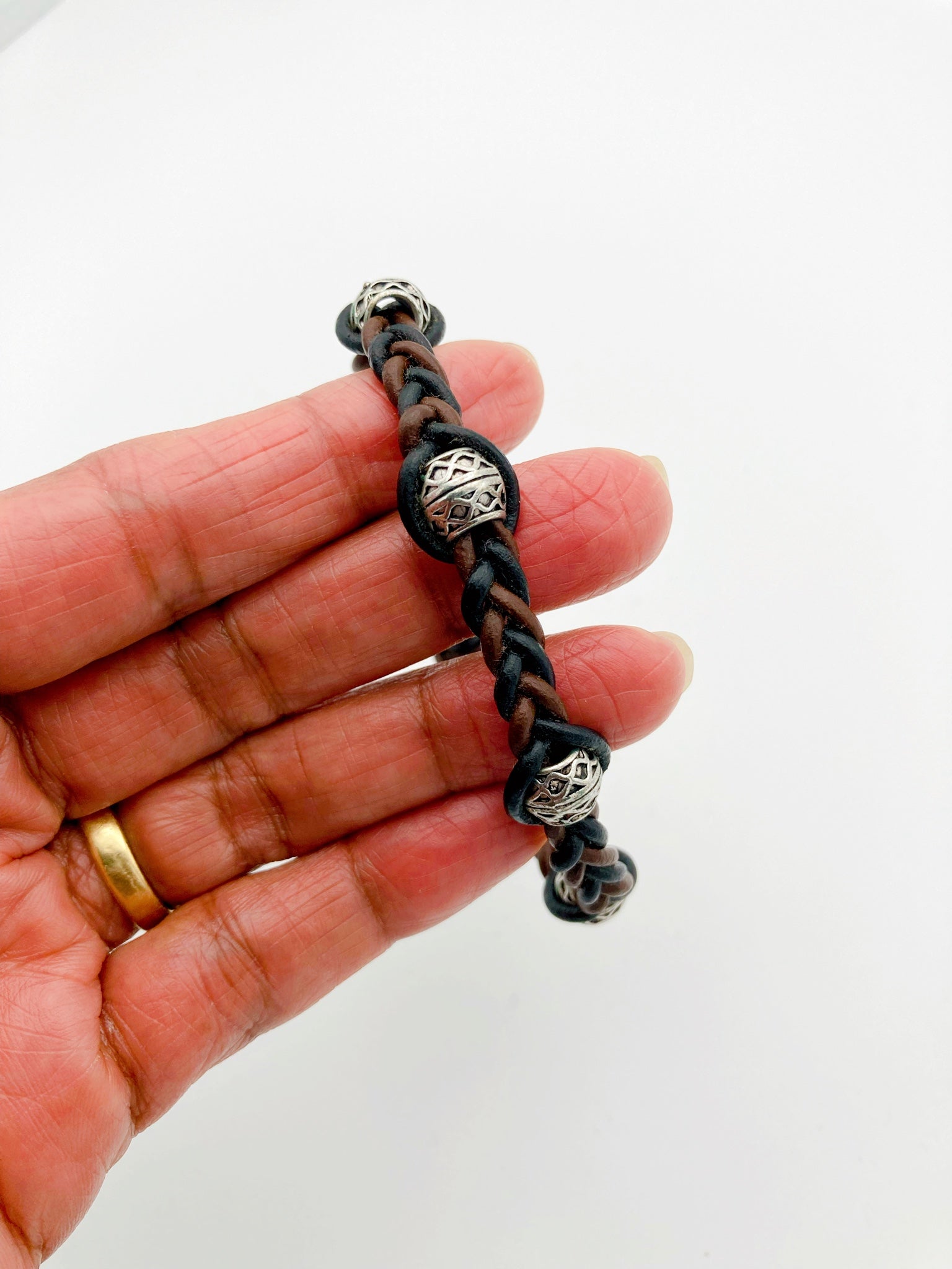 Hand holding woven macrame leather bracelet, by 3D Glass Designs.