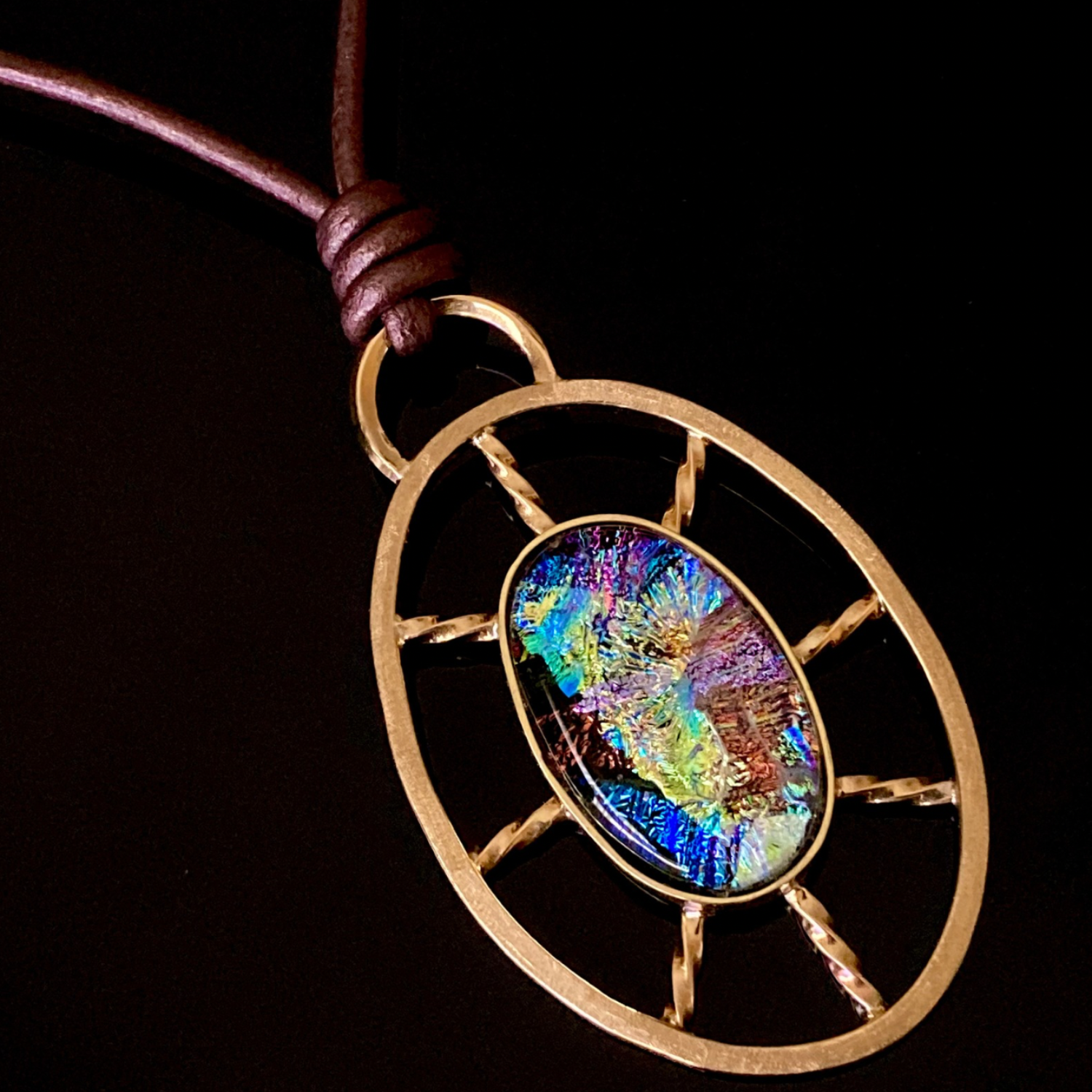 Dichroic glass set in a unique brass pendant, with prongs on left side and a textured bezel on the right side. Pendant is hung on a 29" long hand-knotted multicolor beaded necklace, by 3D Glass Designs.
