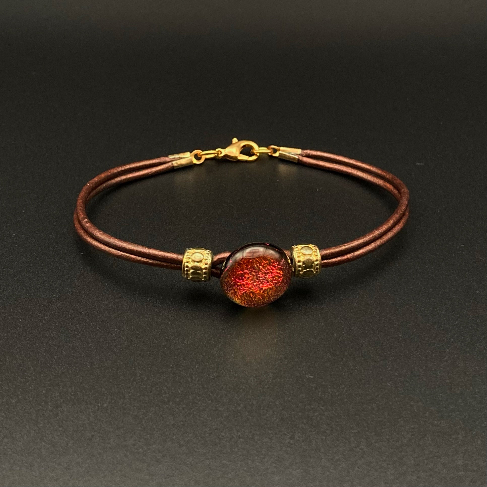 Handmade metallic brown leather bracelet with a round red glass cabochon and gold beads, by 3D Glass Designs.