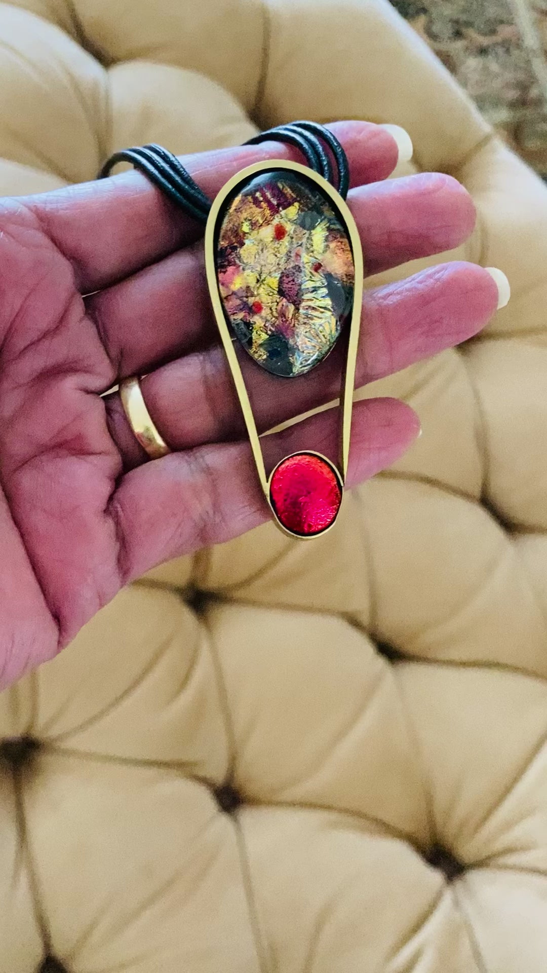 Hand holding dichroic and brass contemporary pendant necklace, by 3D Glass Designs.