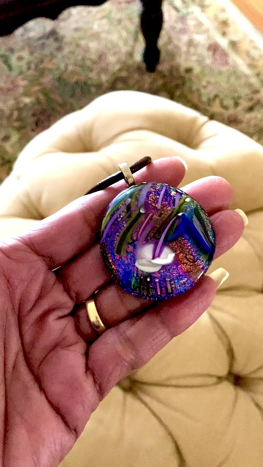 Video of models' hand holding unique dichroic glass pendant with handblown glass details. By 3D Glass Design.