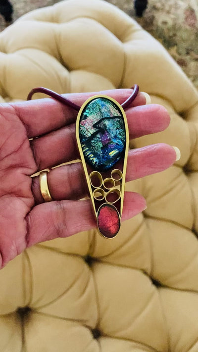 Hand holding Contemporary dichroic glass and bass pendant, handmade by 3D Glass Designs.