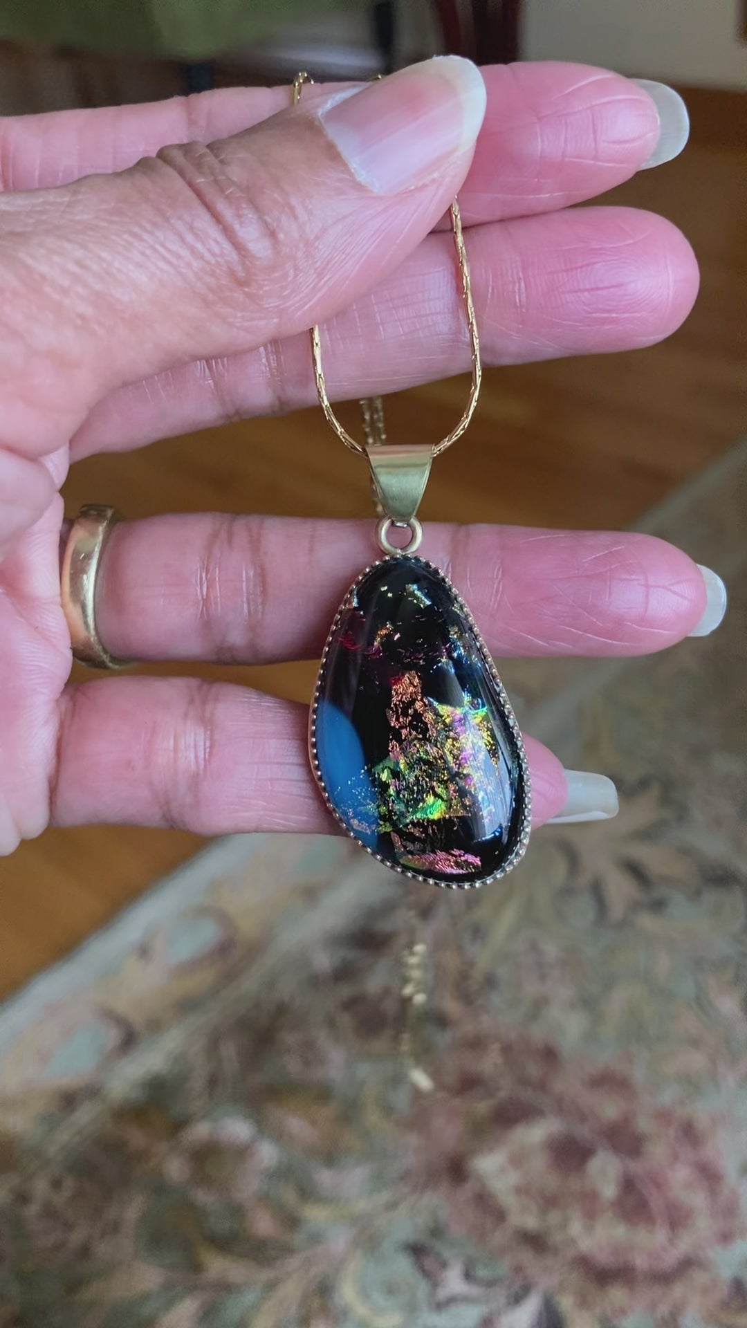 Video of model holding and rotating small dichroic glass pendant. By 3D Glass Designs.