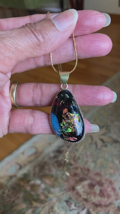 Video of model holding and rotating small dichroic glass pendant. By 3D Glass Designs.