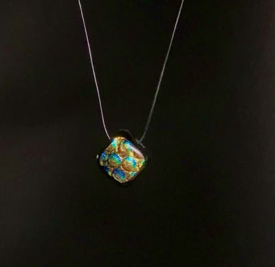 Diamond-shaped dichroic glass rotating against a black background, by 3D Glass Designs.